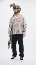 Load image into Gallery viewer, Male model wearing the Contact Coffee camouflage top, with a helmet and weapon system.