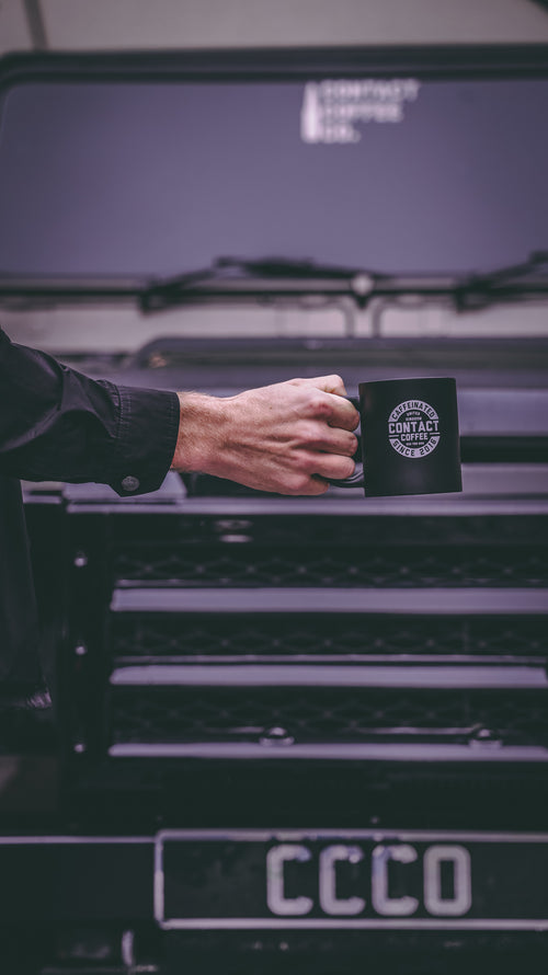 black coffee mug in front of land rover defender