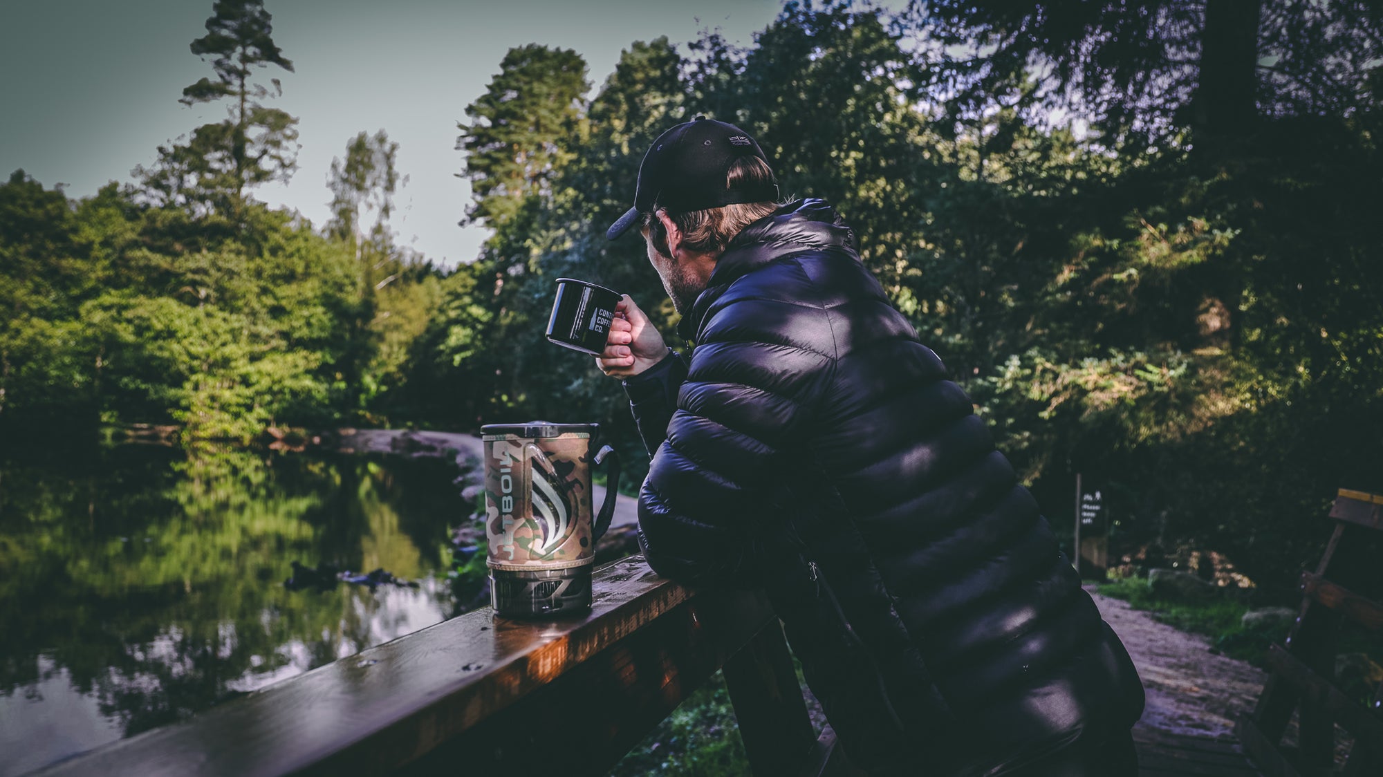man drinking coffee next to water