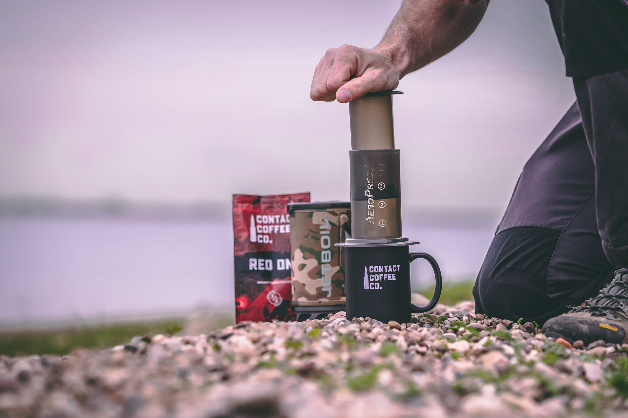 Man making a coffee with an aeropress on the beach